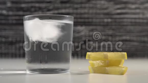 冰块在黑白背景的雾玻璃中随水移动在桌子上躺着几片柠檬视频的预览图