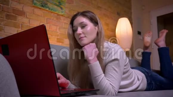 年轻漂亮的白种人深色头发的女商人在笔记本电脑上远程工作躺在电脑上的特写镜头视频的预览图