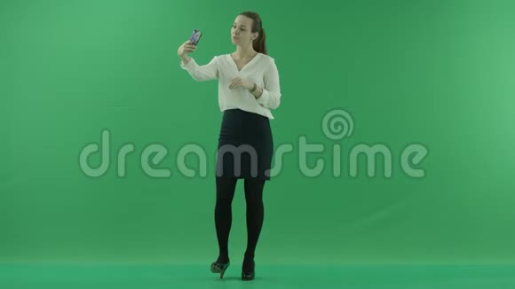 年轻的商界女性正侧着身子在绿色的屏幕前自拍视频的预览图