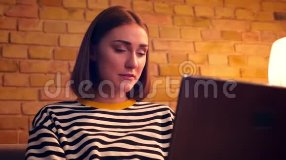 年轻漂亮少女的特写镜头她用笔记本电脑兴高采烈地坐在舒适的沙发上视频的预览图