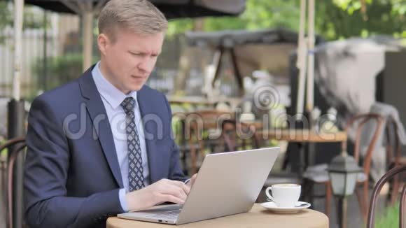 户外咖啡厅使用笔记本电脑头痛的商人视频的预览图