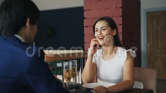 一位穿着奇装异服兴高采烈的年轻女士正和约会的男朋友手拉手坐在桌边讲话视频的预览图