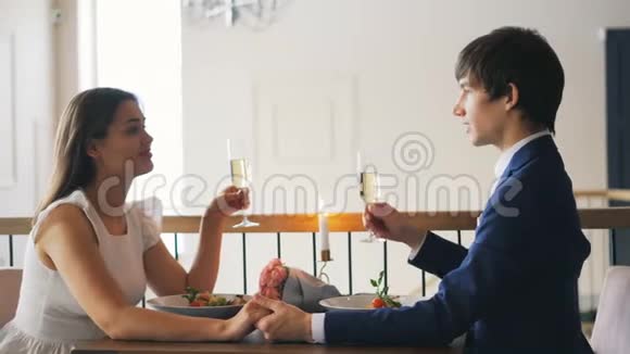 爱的年轻人和他的未婚妻谈着他拿着香槟酒杯然后在浪漫的时候碰着酒杯喝酒视频的预览图