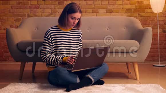 年轻漂亮的女性在网上学习的特写肖像笔记本电脑坐在室内舒适的公寓地板上视频的预览图
