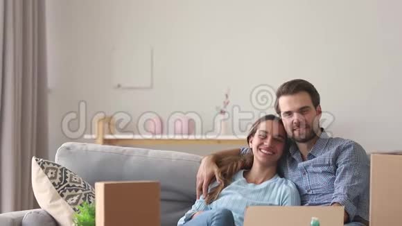 微笑的父母拥抱在沙发上的孩子在搬家的日子里玩耍视频的预览图
