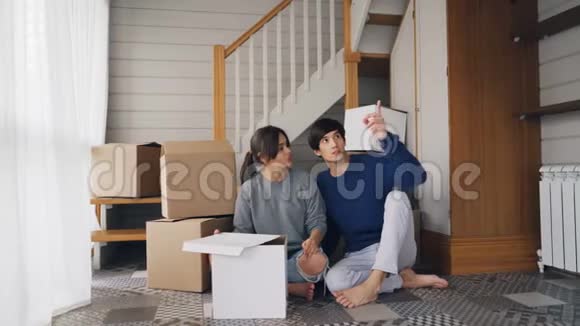 女朋友和男朋友正在谈计划坐在新买的房子的地板上环顾四周表达自己的想法视频的预览图