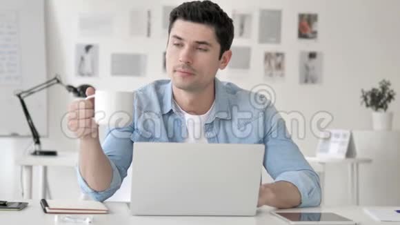 休闲青年在手提电脑工作时喝咖啡视频的预览图