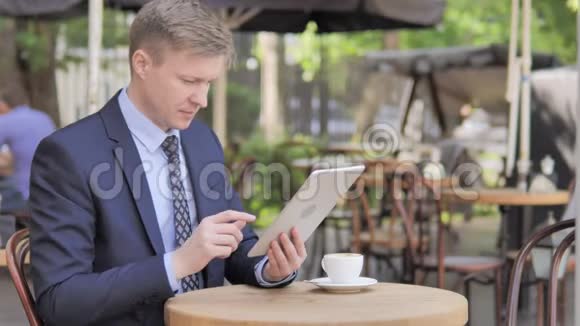 商务人士坐在户外咖啡厅的平板电脑上在线视频聊天视频的预览图