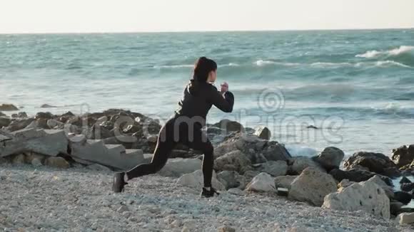 运动型年轻女子在沙滩上做前弓箭步慢动作视频的预览图