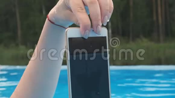 一个拿着湿智能手机的女孩的特写视频的预览图