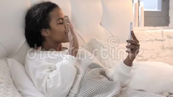 非洲年轻女性在床上放松的在线视频聊天视频的预览图