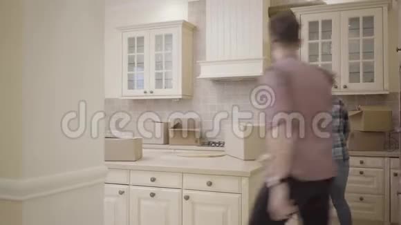 开朗的男人在厨房里追女人男人追他的妻子然后抓住她盒子掉在地板上丈夫视频的预览图
