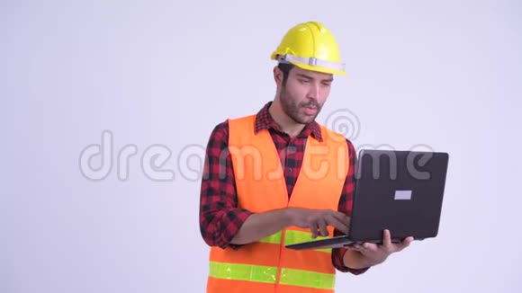 快乐留胡子的波斯建筑工人使用笔记本电脑并竖起大拇指视频的预览图