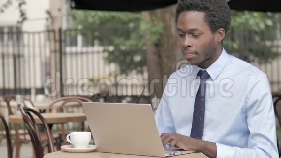 非洲商人坐在户外咖啡厅的在线视频聊天视频的预览图