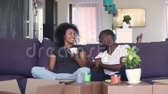 快乐的非洲夫妇在新家喝咖啡拆箱视频的预览图