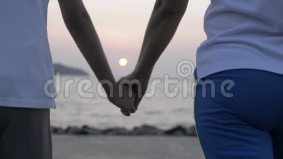 在日出时妈妈和她的女儿一起走着牵着手来到海岸那里有美丽的海洋风景视频的预览图