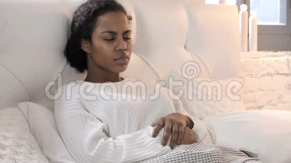 带头疼的非洲年轻女性在床上放松视频的预览图