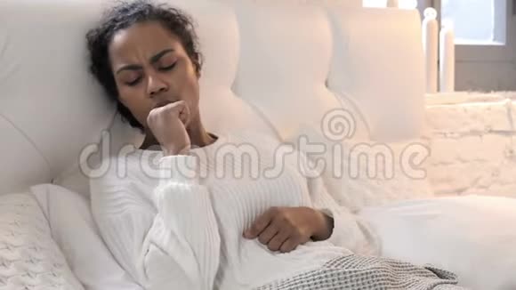 生病的非洲青年妇女在床上放松时咳嗽视频的预览图