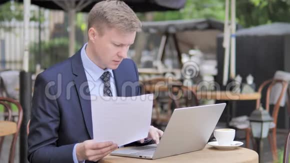 商务人士阅读合约及在户外咖啡厅使用手提电脑视频的预览图