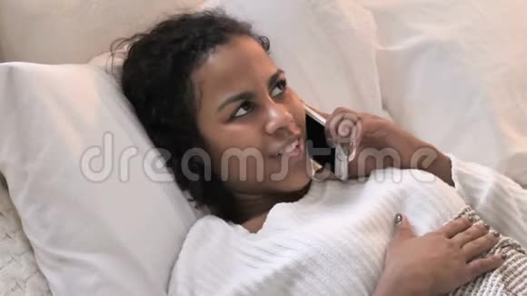 青年非洲妇女在床上打电话的最高看法视频的预览图