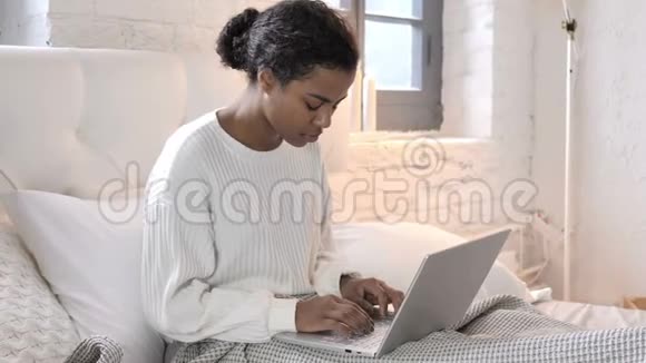 令人震惊的年轻非洲妇女想在床上笔记本电脑上取得成果视频的预览图