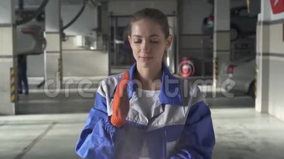 女专家在汽车服务中辛勤工作后将手套上的灰尘和污垢粉碎的肖像视频的预览图