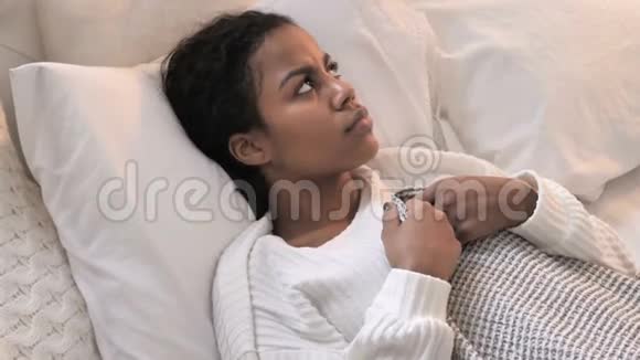 惊魂未定的非洲年轻女性躺在床上的最高视角视频的预览图