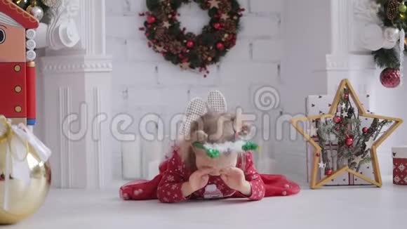 穿着红色连衣裙的小可爱女孩在房间的地板上躺着圣诞装饰视频的预览图
