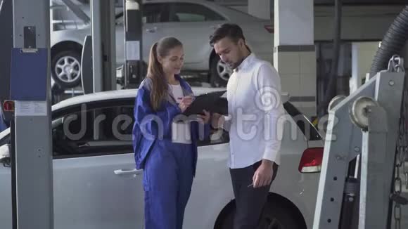漂亮女孩汽车修理工拿着汽车的数据签名拿着钥匙和握手年轻的帅哥在车上视频的预览图