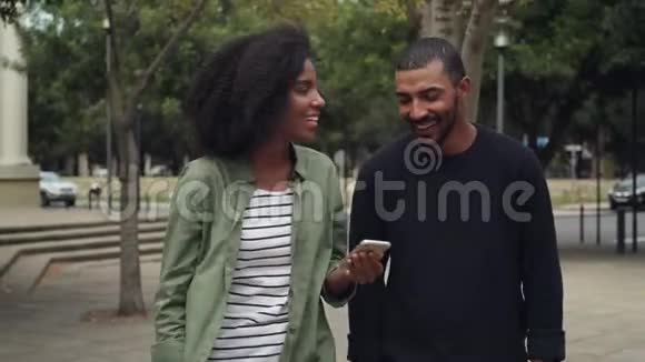非洲年轻夫妇在街上散步时使用手机视频的预览图