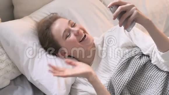 躺在床上的年轻女性在线视频聊天的最佳视角视频的预览图