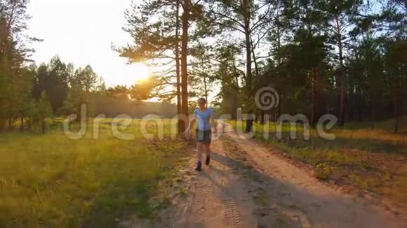 穿着短裤和蓝色眼镜的女孩在日落时走在乡间小路上视频的预览图