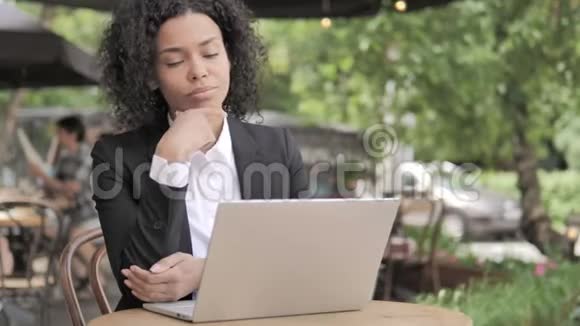 想着快乐的非洲女人在手提电脑户外咖啡厅视频的预览图