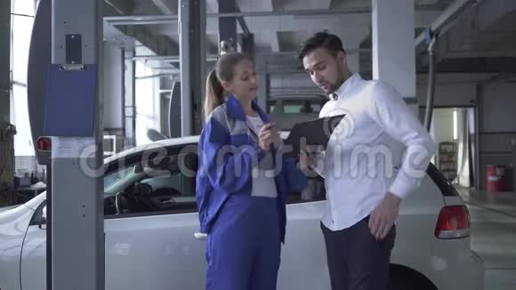 女汽车专家收集汽车检验数据年轻的帅哥把签名放在车里视频的预览图