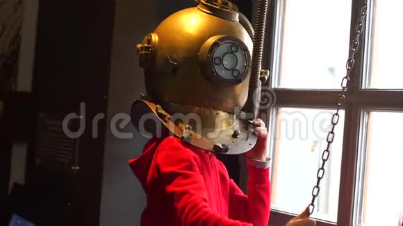 一个男孩站在一个旧的潜水头盔里视频的预览图