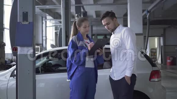 女汽车专家收集汽车数据供年轻有魅力的汽车服务人员检查视频的预览图