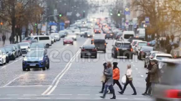 人们在繁忙的城市街道上过马路交通高峰期一群无名行人穿过繁忙的城市视频的预览图