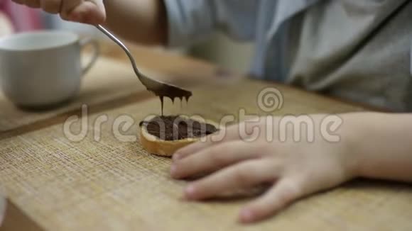 小男孩晚饭后吃一块面包和巧克力糊近距离舔勺子视频的预览图
