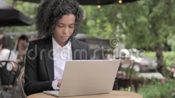 咳嗽的非洲妇女在户外咖啡厅的笔记本电脑上工作视频的预览图