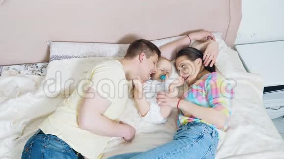 可爱的父母和他们可爱的小儿子躺在床上视频的预览图