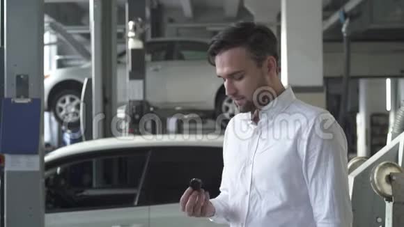 汽车服务部门的年轻帅哥扔出他的汽车钥匙在他的汽车背景上微笑视频的预览图