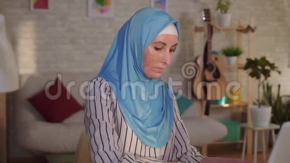 肖像年轻的穆斯林妇女戴着头巾脸上有烧伤的伤疤在笔记本电脑上工作视频的预览图