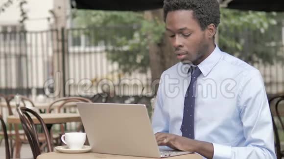 非洲商人坐在户外咖啡厅边打电话视频的预览图