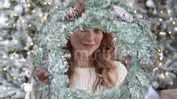 圣诞树背景下一位穿着白色毛衣微笑的女士的新年画像视频的预览图