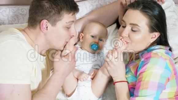 可爱的父母和他们可爱的小儿子躺在床上视频的预览图