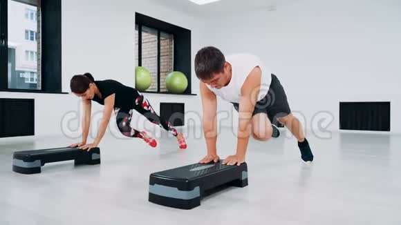 一个男人和一个女人在健身工作室做俯卧撑使用台阶平台视频的预览图