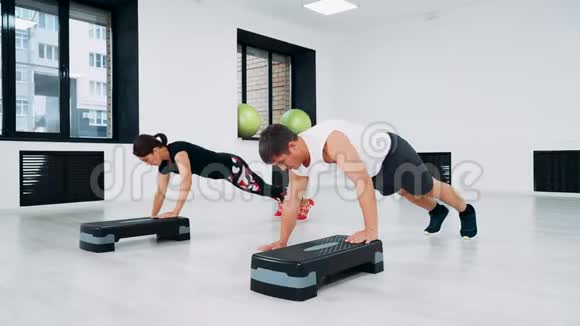 一个男人和一个女人在健身工作室做俯卧撑使用台阶平台视频的预览图