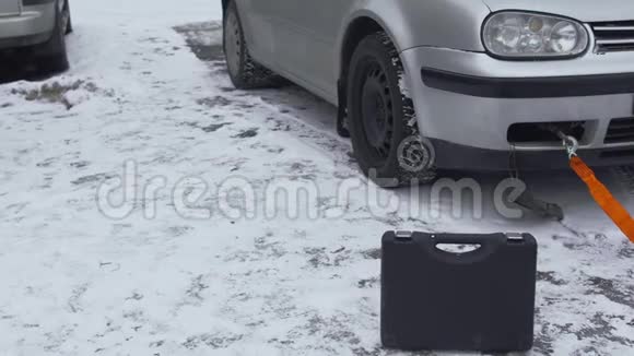 一条灵活的绳子拉着一辆破车特写镜头冬天白天在停车场的院子里故障或视频的预览图