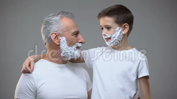 在剃须泡沫中带剃须刀男人仪式的祖父和孙子视频的预览图