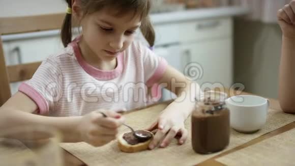 晚饭后女孩在一块面包上涂上巧克力酱然后吃它视频的预览图